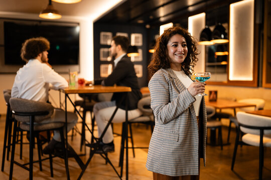 Woman holding cocktail networking and socializing in bar lounge