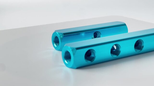 Two blue anodized aluminum manifold blocks for pneumatic systems. High-quality industrial distribution manifolds with multiple threaded ports for air and fluid control, isolated on a light background
