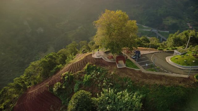 Epic sunrise orbit over Miradouro Lombo do Pico in Madeira, tourist using observation binoculars on a scenic viewpoint near a car with roof top tent, lush green mountains and Atlantic ocean view.