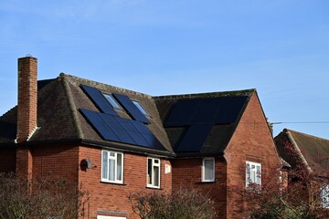 Red brick house roof with multiple residential solar panels in UK © Ruslan