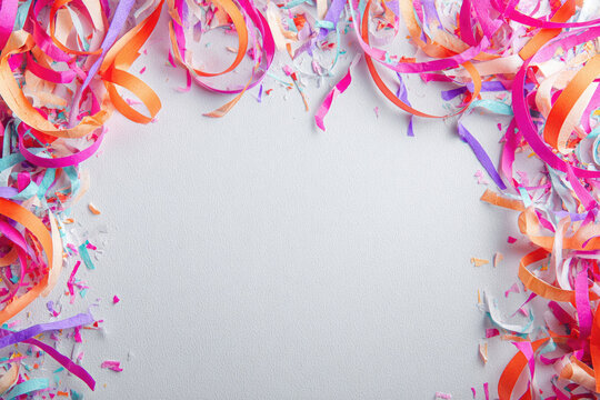 Colored serpentine ribbons form a festive frame on a light background. Space for text.