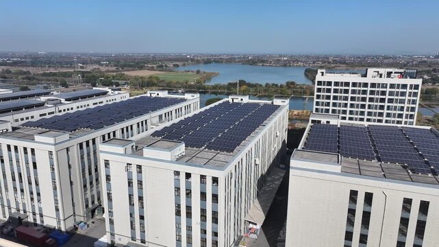 Aerial view of modern building complex with solar panels installed on rooftops near a lake