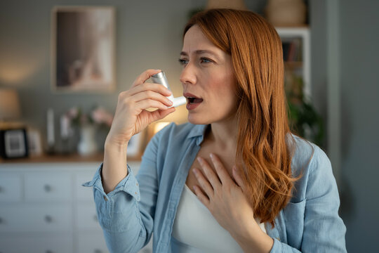 Woman experiencing asthma attack using bronchodilator inhaler