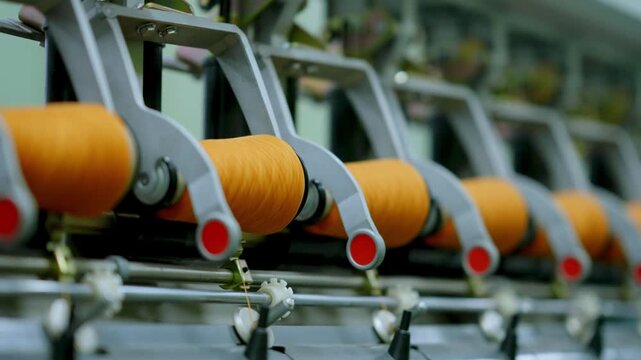 Textile factory spinning machine with orange yarn running at high speed