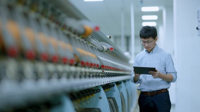 Technical staff in factory workshop holding tablet for equipment inspection
