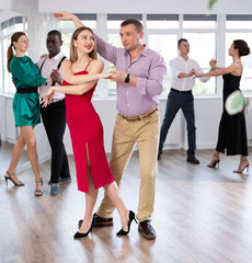 Fototapeta premium During rehearsal of reporting concert, man and woman participants of dance workshop perform figure waltz. Group training and rehearsal, preparation for competitions