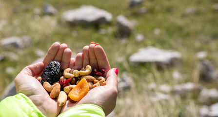 Close-up of hands holding healthy trail mix with nuts and dried fruits outdoors. Concept of clean eating, energy snack, hiking, wellness, and active lifestyle.  © Sejla