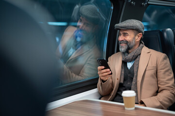 Fototapeta premium Mature man traveling by train using mobile phone