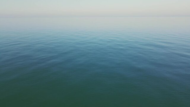 Aerial view of calm azure sea with gentle waves in warm autumn daylight, Batumi Georgia. Minimal 4K drone shot with peaceful meditative mood.