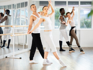 Fototapeta premium Young man and young woman dancers rehearsing pair ballet in studio