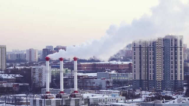 Industrial heating plant with smoke stacks in a winter city, urban energy production, cold weather conditions, industrial infrastructure and environmental concept