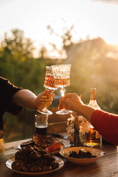 Sunset picnic toast with crystal glasses over rustic outdoor dinner table
