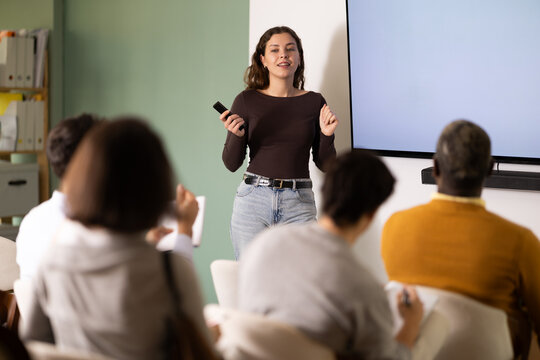 Young woman teacher gives lecture to multinational group of students in lecture hall