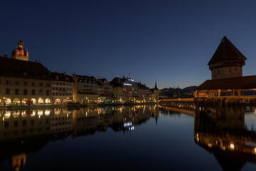 Obraz premium Lucerne cityscape at dusk with historic buildings and Chapel Bridge reflected in the Reuss river