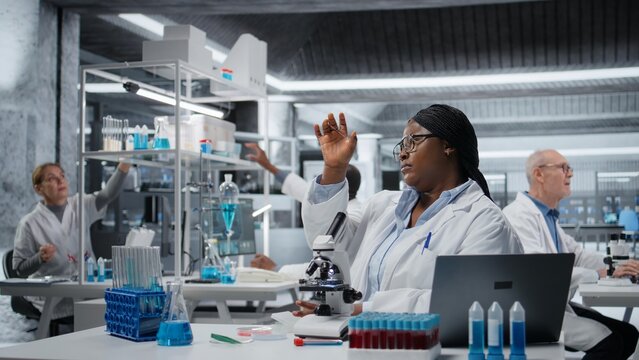 Female scientist looking at patient biopsy slide to detect abnormal cellular growth. African american woman preparing microscope in hospital lab for diagnostic confirmation, camera A