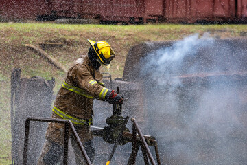 Fototapeta premium Firefighter in fireproof cloth is opening water valve near burning building with high flame for fire extinguish risk rescue mission and accident management