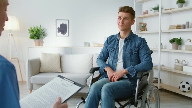 Psychological support for people with disability. Middle aged man wheelchair user talking to professional psychologist, doctor making notes, zoom in, slow motion