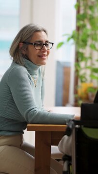 Cheerful mature woman with a physical impairment sitting at a table. Positive person with spina bifida engaged in a lively conversation