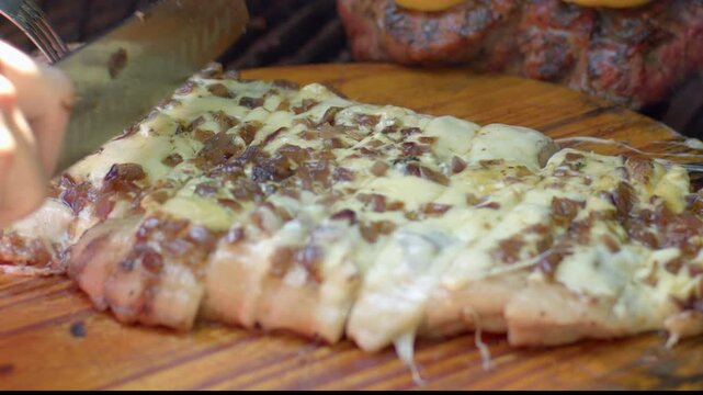 Slicing juicy ​​pork with cheese and juicy onions in a barbecue asado Slowmotion