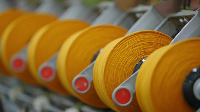 Close-up of yellow yarn spools arranged in a textile factory production line