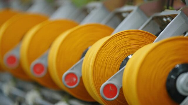 Close-up of yellow yarn spools arranged in a textile factory workshop