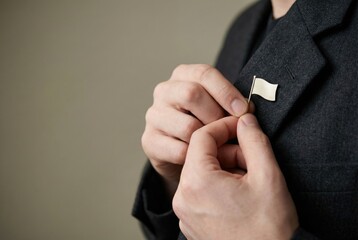 Fototapeta premium A person pinning a small, blank, flag-shaped pin mockup onto a jacket lapel.