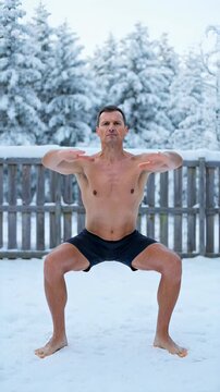 Shirtless fit man performing Qi Gong horse stance in a snowy winter forest, demonstrating cold exposure and mental resilience for biohacking concepts.