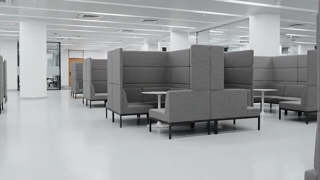 Empty modern open-plan office with grey booth seating and tables