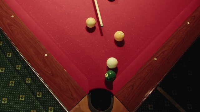 Overhead view of corner cluster on red table with balls near pocket. Hit with cue and try to score a point. Strong geometry and symmetry, tactical positioning for next shot. Moody club lighting
