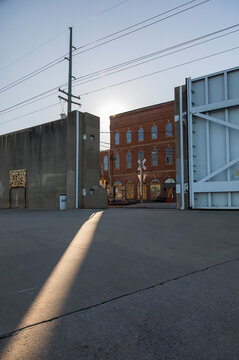 Streak of Sunlight Through the Flood Gate.  Sunlight filters through the riverwalk gate, casting a sharp, angular shadow on the concrete ground. 
