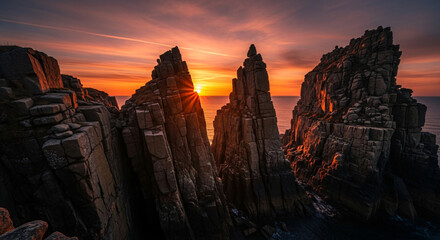 Naklejka premium Dramatic Golden Sunset over Rugged Coastal Rock Formations