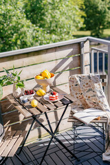 Obraz premium Balcony setup for enjoying breakfast on a sunny day with fresh fruits and flowers