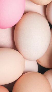 Slow camera zoom moves across egg background, revealing natural shells mixed with bright Easter painted colors, creating festive vertical texture for seasonal food and holiday themes.