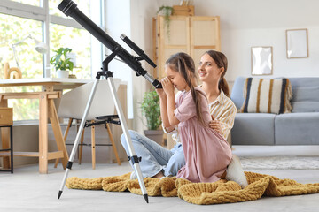 Fototapeta premium Little girl with her mother looking through telescope at home