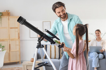 Fototapeta premium Little girl with her father and telescope at home