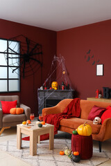 Naklejka premium Interior of living room decorated for Halloween with sofa, armchair and fireplace