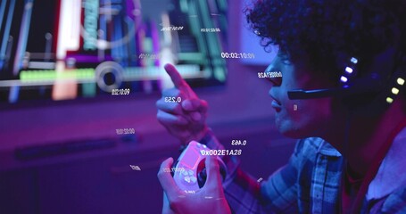 Pointing gamer in plaid hoodie LED-headset holding gamepad at desk with monitor HUD, copy space © vectorfusionart