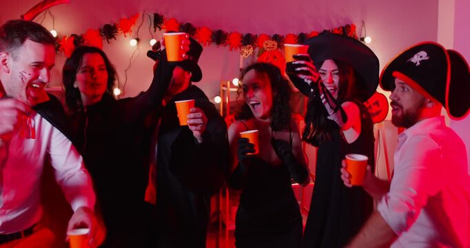 Cheerful group of friends dancing together to music at a halloween party at home. Fun and lively atmosphere, enjoying celebration, friendship, and excitement in a joyful gathering.