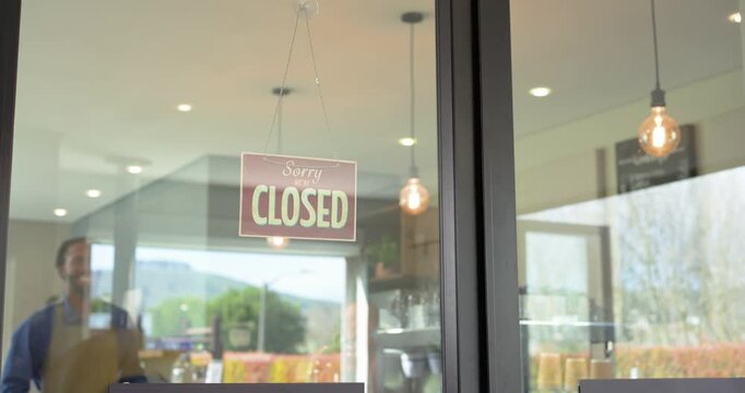 African American male barista flipping closed sign opening door, entering cafe to open, copy space