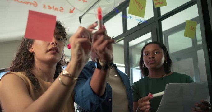 African team following left woman placing red sticky note on glass, writing pie chart for planning