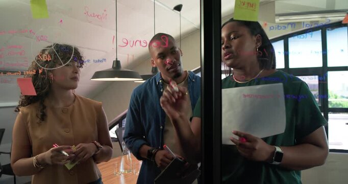 African American team pointing at glass notes in office, driving planning with markers and stickies