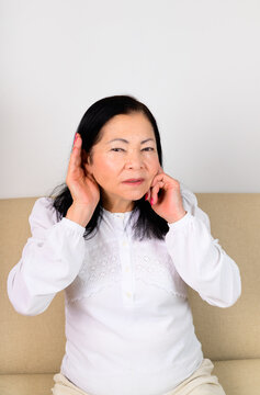 Senior woman touching ear, hearing loss awareness, audiology, aging health and listening difficulty concept.