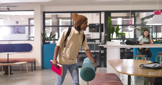 African American man entering campus lounge from left placing pink folder greeting peer thumbs-up
