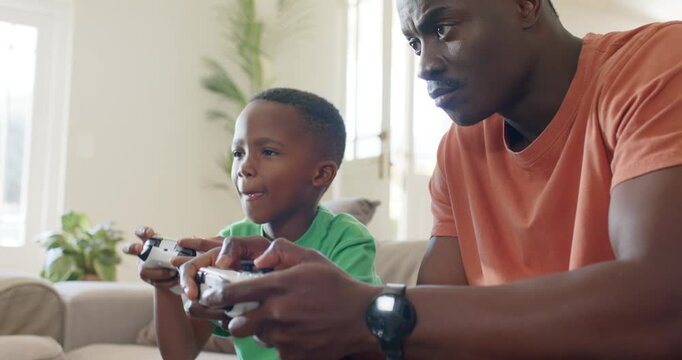 African American father and son reacting to game start, father teaching son on white controllers
