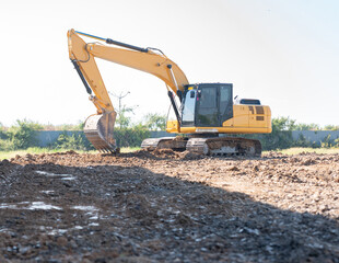 excavator parked on a dirt construction site with its bucket lowered to the ground during earthmoving operations.