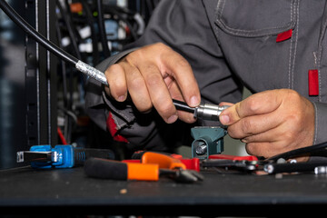 Close up of technician hands soldering RF cable in telecom server room. Professional electronic work, network maintenance, data transmission and modern communication technology concept.