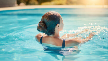 Woman swimming in serene outdoor pool, clear blue water, relaxation, vacation, summer, wellness, leisure, tranquility, holiday, luxury resort.