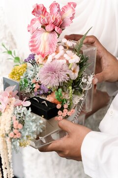 Close up of Indonesian Muslim couple holding a decorative wedding gift box with flowers and gold bar