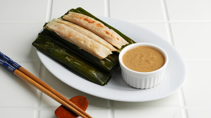Otak-otak Tengiri, made from fish and flour covered with banana leaf. Served with peanut sauce. Indonesian food
