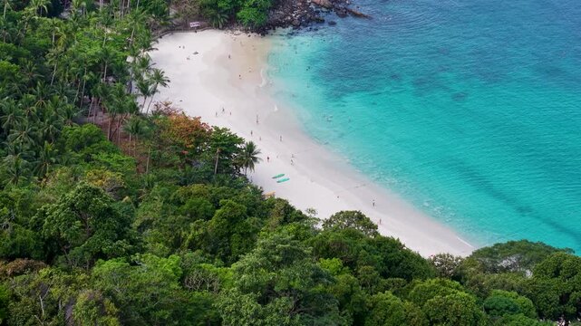 A breathtaking view of a pristine beach, where crystal-clear turquoise waters meet a stretch of sun-kissed sands, embraced by lush green vegetation. 